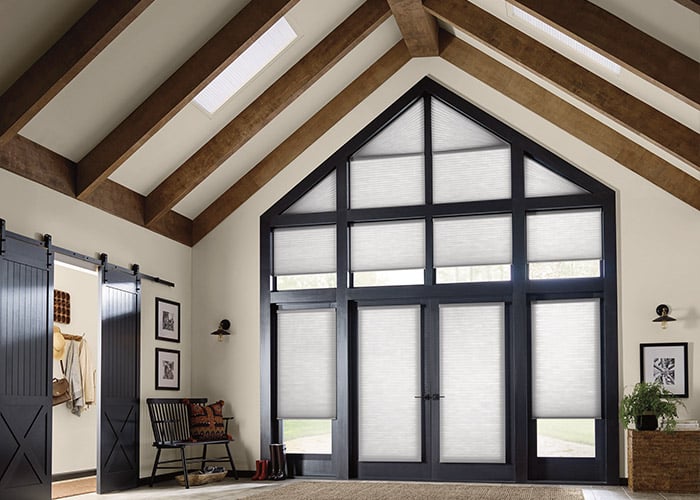 Beautiful interior featuring large black-framed barn doors with white shades, vaulted ceiling with wooden beams, cozy seating area, and decorative artwork.