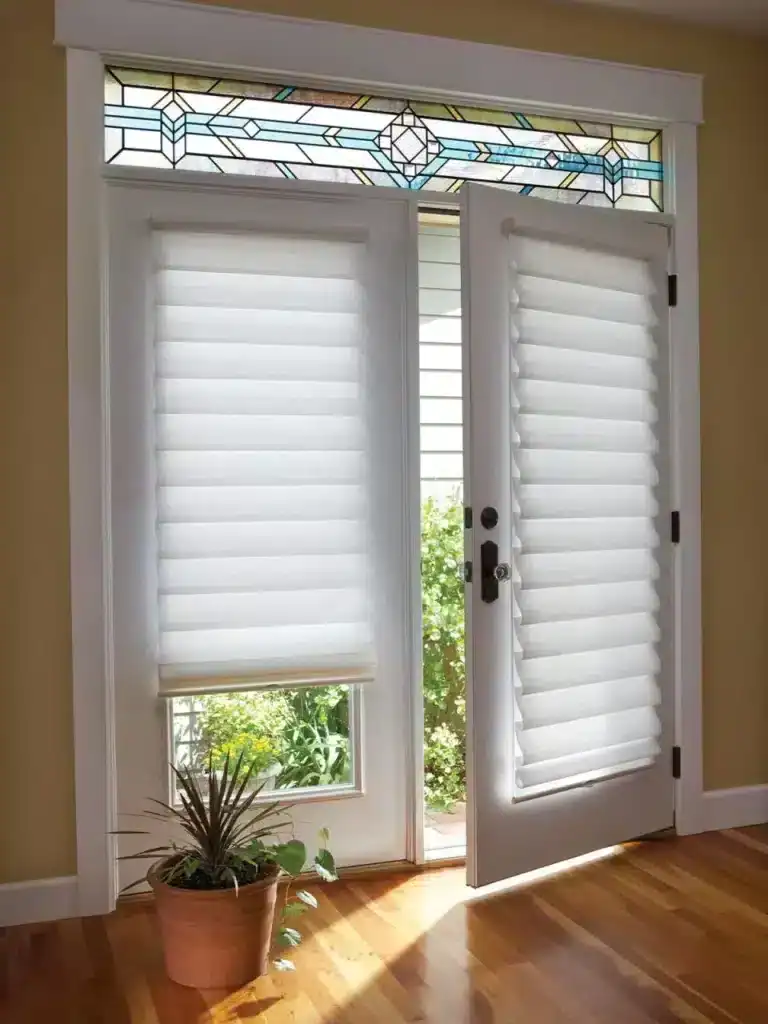 Bright front door with stained glass transom and white plantation shutters, inviting entrance, natural sunlight, wooden floor, indoor plant, home improvement, exterior view, decorative window.
