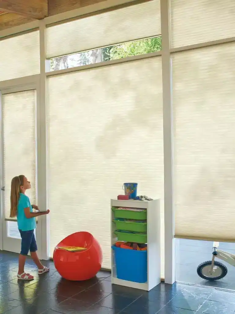 Bright indoor space with beige window blinds, allowing natural light, children's toys and furniture for play and learning.