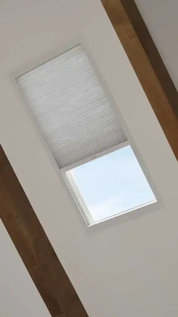 Bright skylight with roller blind, allowing natural sunlight into a minimalist room, showcasing ceiling detail and modern decor, elegant and functional window feature.