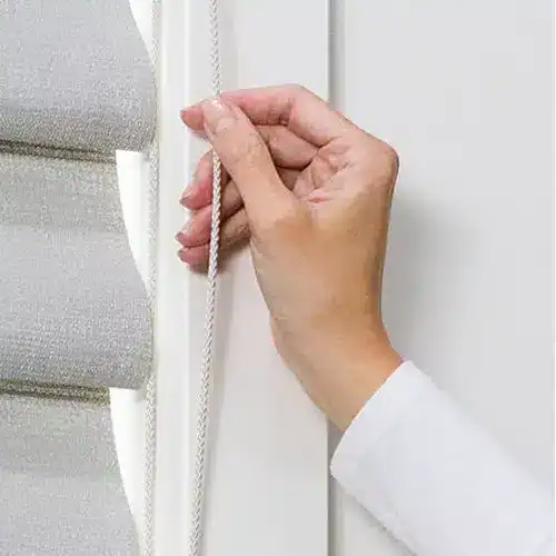 Close-up of hand pulling a cord to operate window blinds outdoor or indoor.