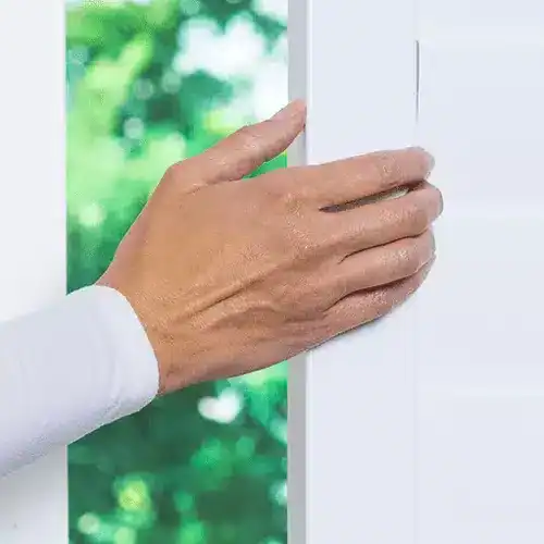 Close-up of a hand locking a white window for security and safety.