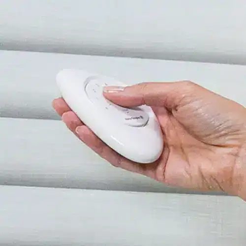 Hand holding a remote control cleaning device for dust and debris removal in home or office settings.