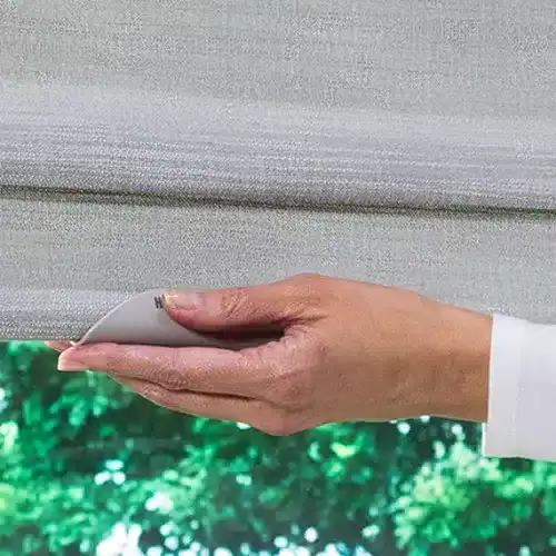 Close-up of a person’s hand smoothly operating a white window blind.