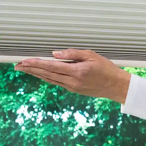 Close-up of a person inspecting or cleaning window blinds or shutters, emphasizing window care and home maintenance.