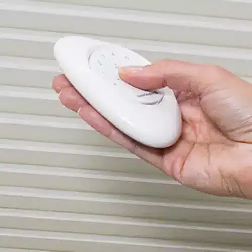 A white power strip with multiple outlets held in a person's hand.