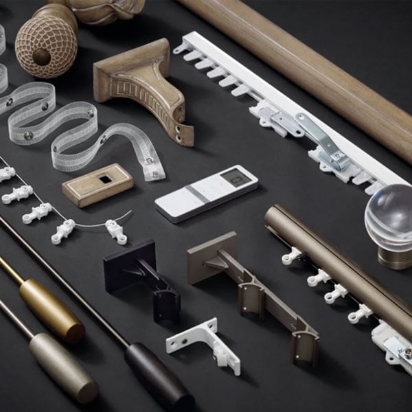 Assorted drapery hardware parts including brackets, rods, hooks, and finials arranged on a black surface for display.