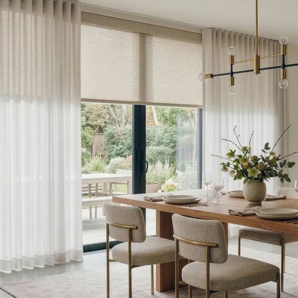 Elegant dining room with sheer and blackout curtains, sliding glass door, and contemporary chandelier, creating a cozy and stylish atmosphere.