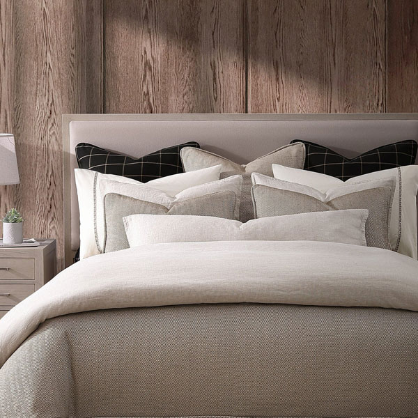 Elegant bedroom with neatly made bed, soft pillows, and wooden wall background, perfect for a restful sleep environment.