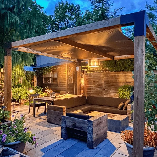 Cozy outdoor patio with a shaded seating area, wooden furniture, potted plants, and ambient lighting for relaxing evenings.